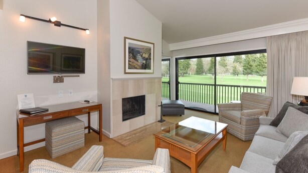 Ein modernes Wohnzimmer mit Kamin, Fernseher und Blick auf einen Golfplatz.