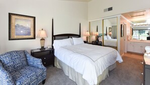 A bedroom with a large bed, a chair, a dresser, a mirror, and a painting on the wall.