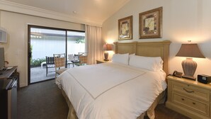 A hotel room with a large bed, two bedside lamps, a desk with a telephone, and a view of an outdoor patio with chairs and a table. - 657 S At Silverado Studio Bedroom Residence by Redawning (Napa)