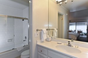 Un baño moderno con ducha de vidrio, un espejo grande y un lavabo blanco con tocador.