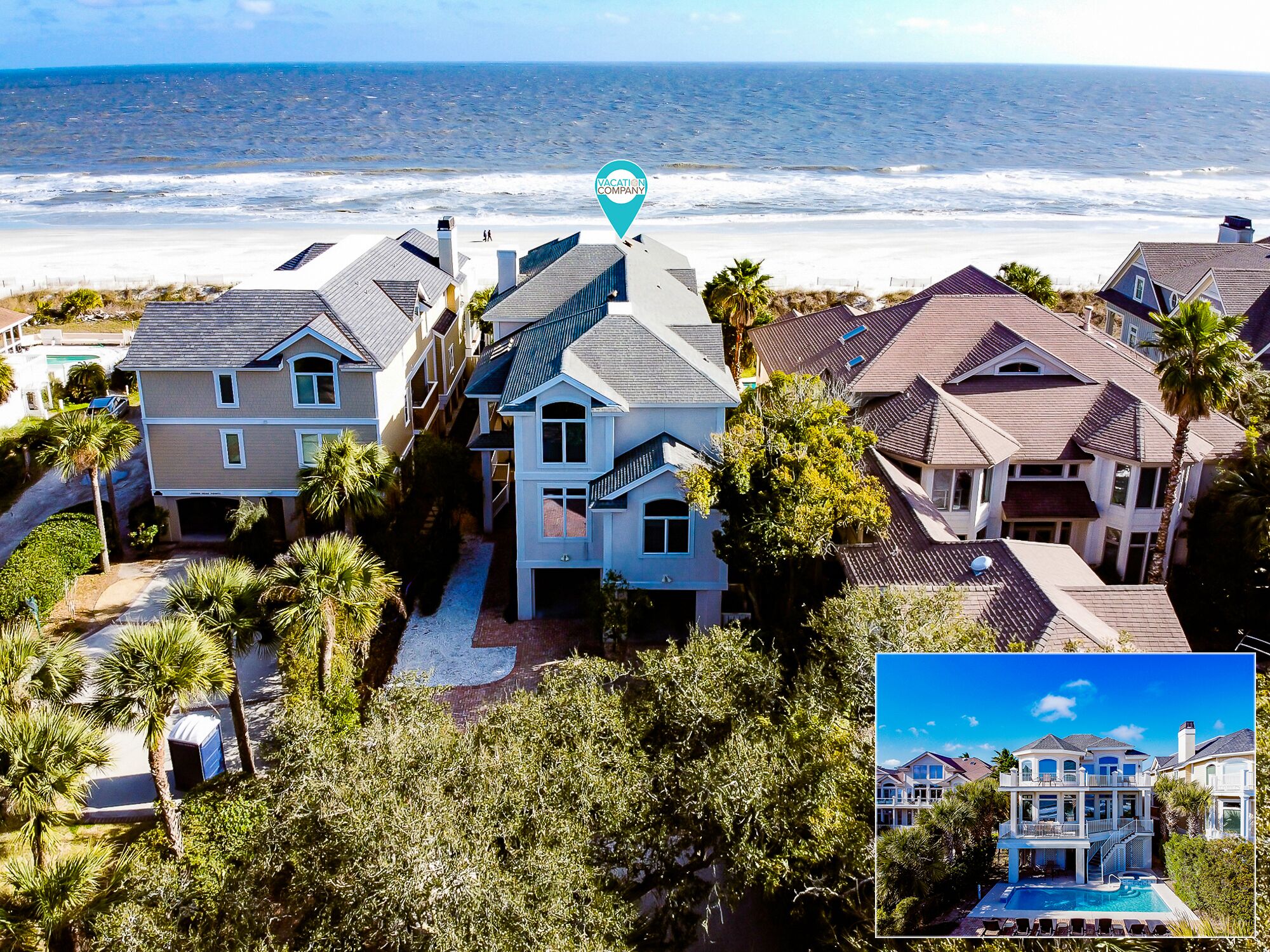 A coastal residential area with houses, a beach, and a clear sky.