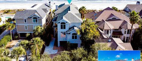 A coastal residential area with houses, a beach, and a clear sky.
