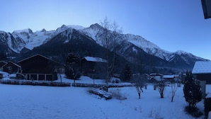 Un paysage montagneux enneigé, avec une rangée de maisons en bois au premier plan.