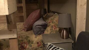Een gezellige kamer met een bed, een nachtkastje met een lamp en een welkomstkussen.