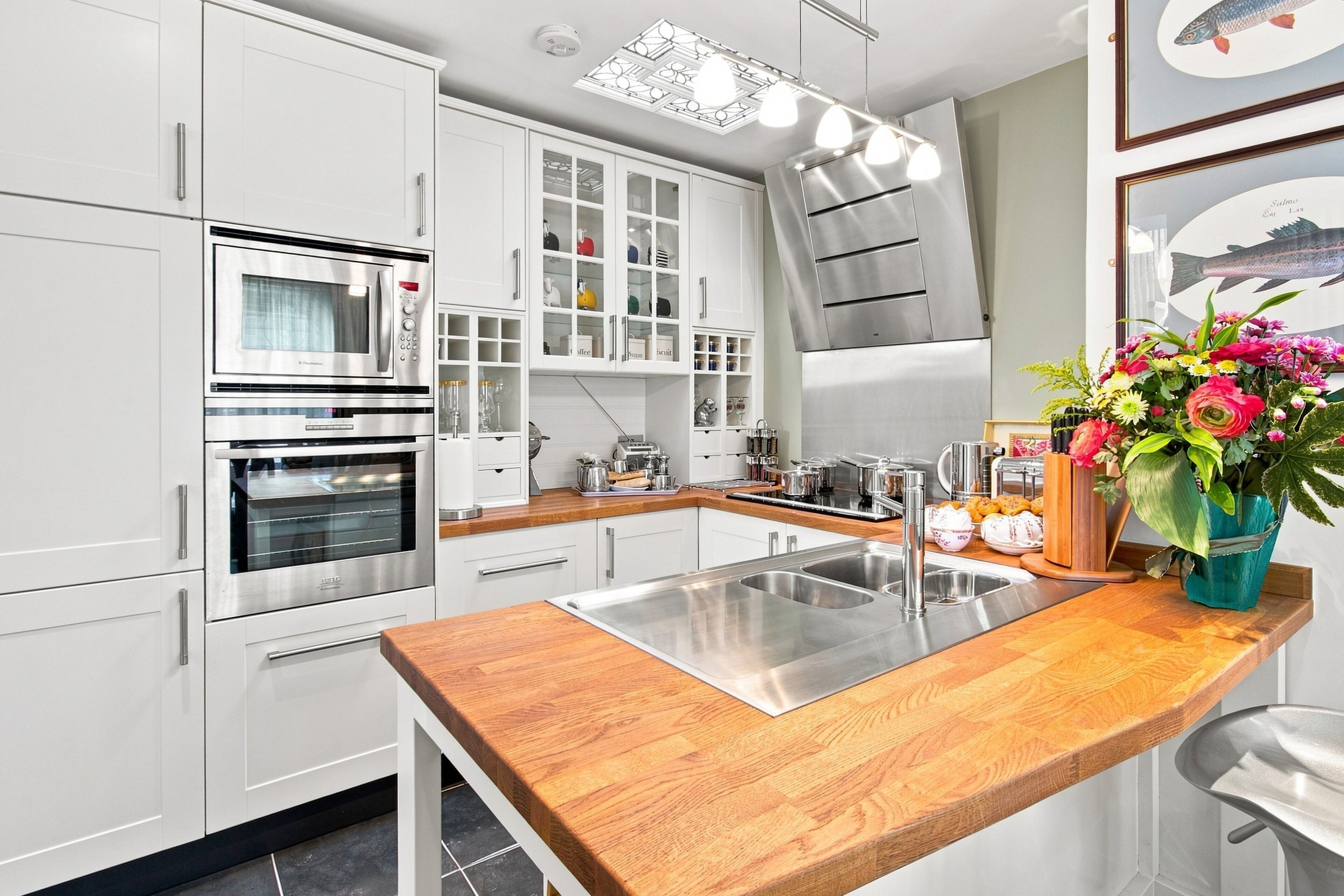 Una cucina moderna con elettrodomestici in acciaio inossidabile, un piano di lavoro in legno e un lavello incassato.