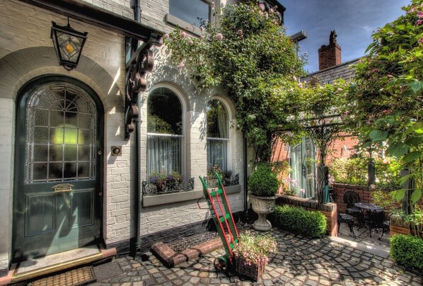 A traditional building with arched windows, a brick chimney, and a cobblestone courtyard.