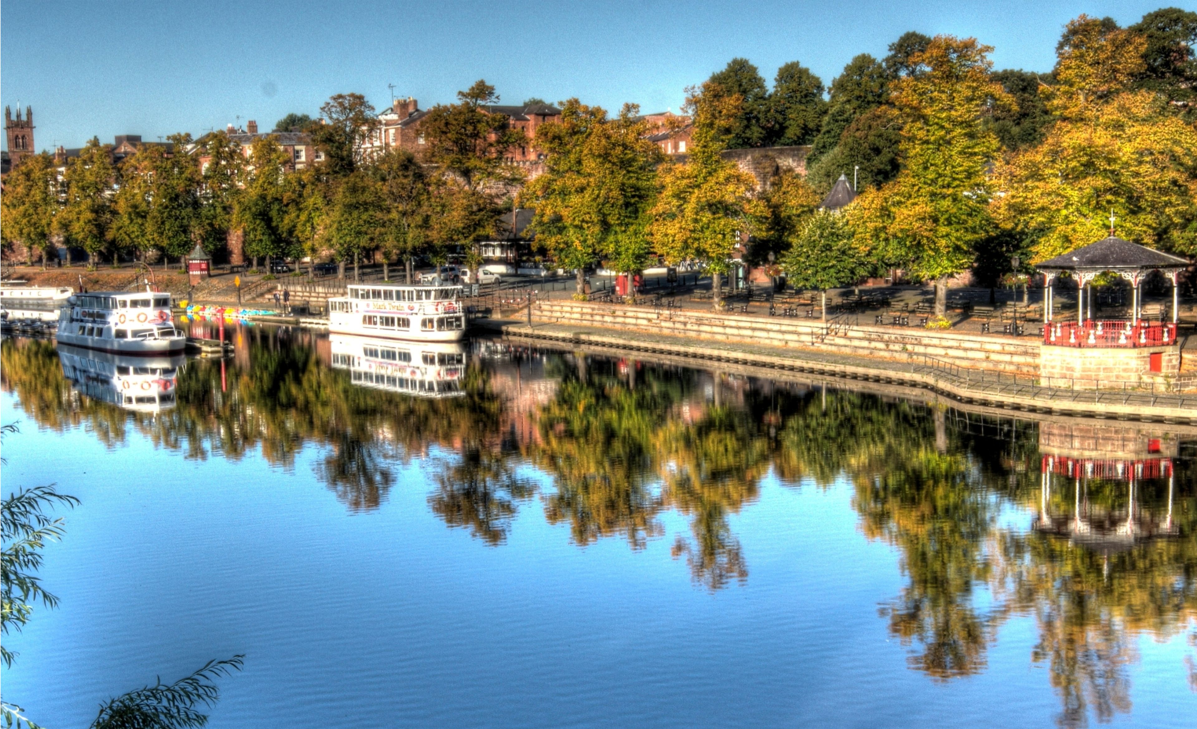 A river with a sightseeing cruise boat, a bridge, and a gazebo.