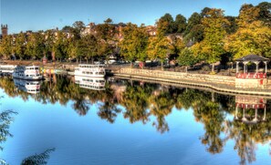 A river with a sightseeing cruise boat, a bridge, and a gazebo.