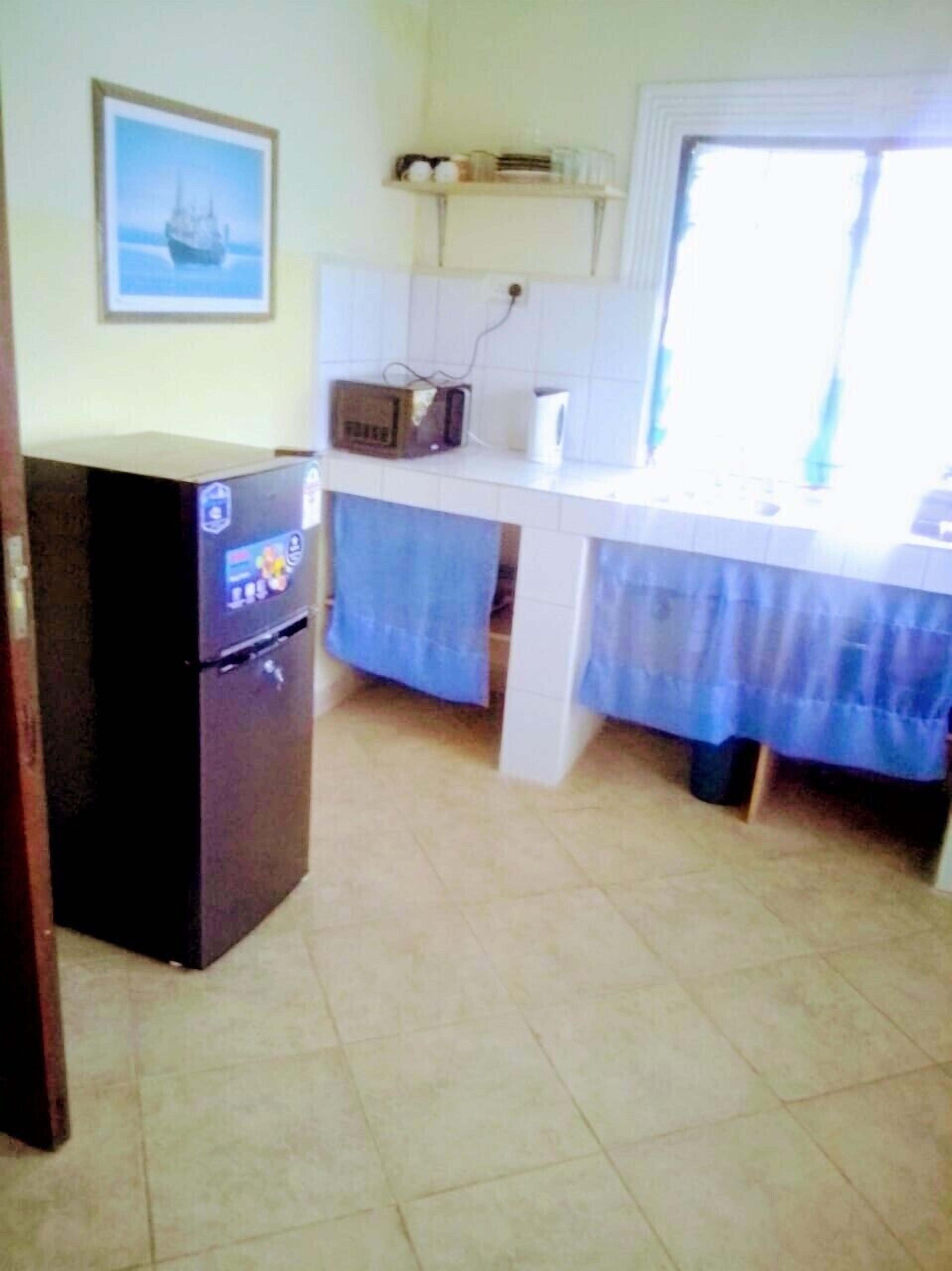Cocina compacta con refrigerador, microondas y ventana con cortinas.