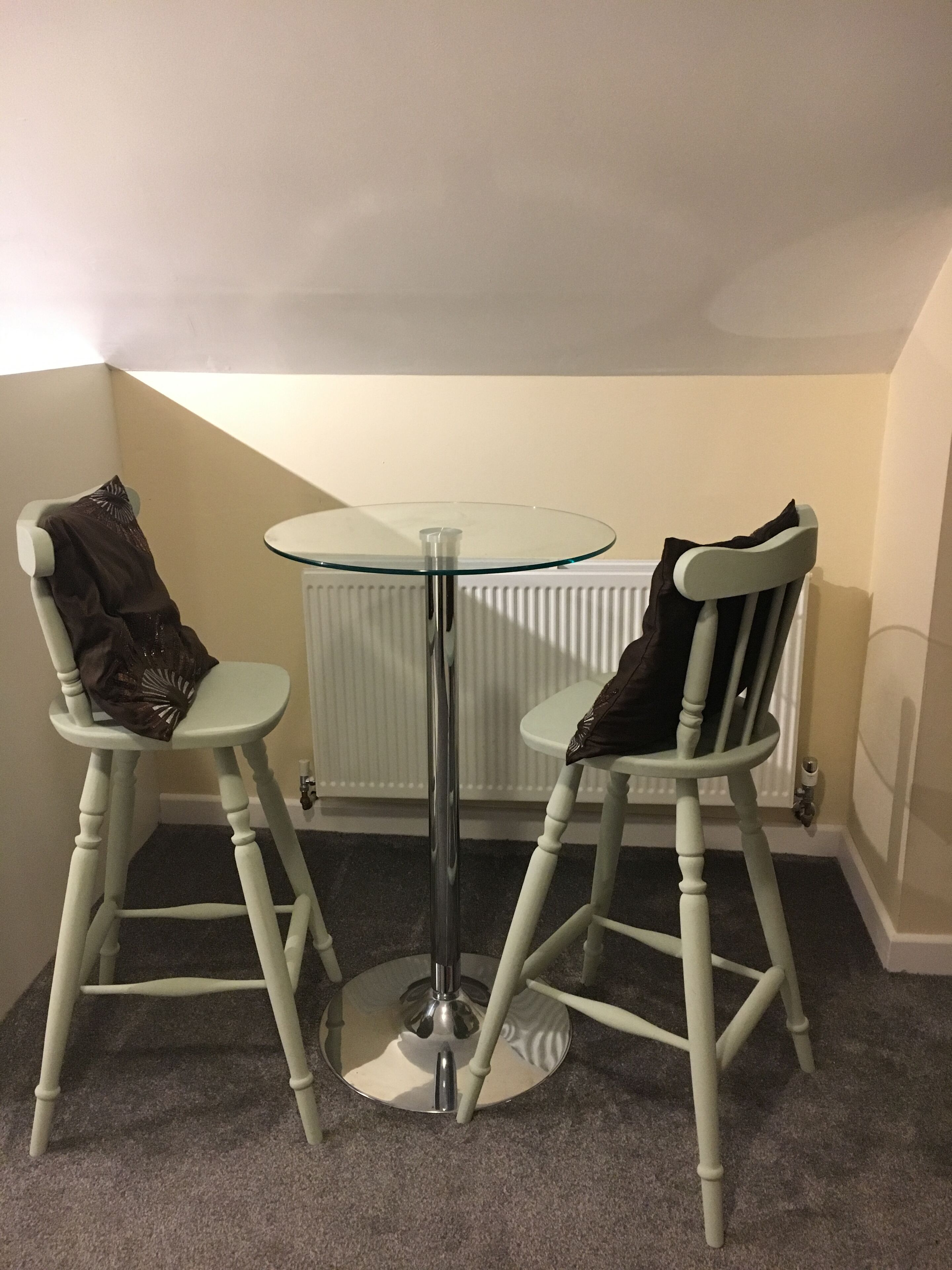Une petite pièce avec deux chaises blanches et une table dont le plateau est en verre.