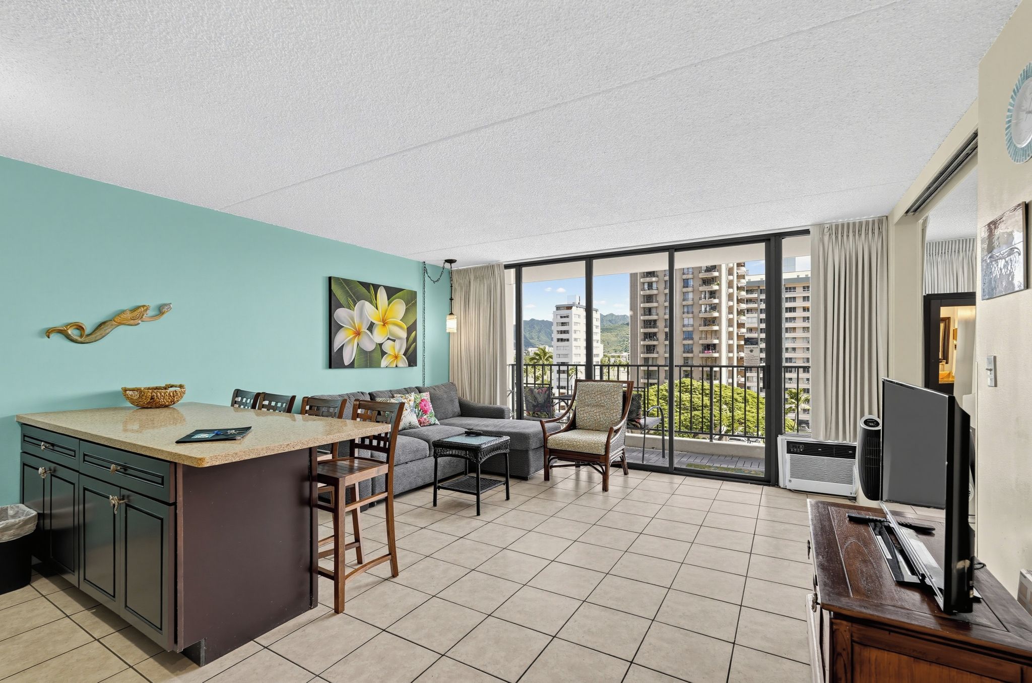 Ein modernes Wohnzimmer mit Küchenbereich, einem Esstisch und einem Balkon mit Blick auf die Stadt.