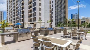 Un patio al aire libre con una parrilla, asientos y vistas de edificios altos.