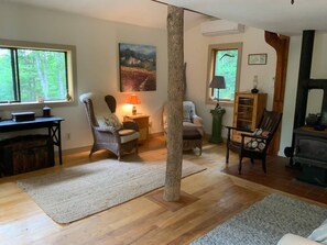 A cozy living room with a fireplace, wooden flooring, and a large window.