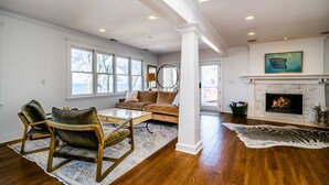 Un salon spacieux doté de planchers en bois franc, d’une cheminée, d’une grande fenêtre offrant une belle vue et d’un coin salon confortable.