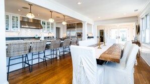 Une cuisine spacieuse équipée d’appareils modernes, un coin repas avec une grande table en bois et un espace détente avec des fauteuils en osier.