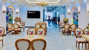 A spacious hotel lobby with ornate chandeliers, floral wall art, and a central seating area with tables and chairs. - Hata hotel (Quy Nhon Nam)