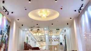 A hotel lobby with a grand staircase, a chandelier, and a reception desk. - Hata hotel (Quy Nhon Nam)