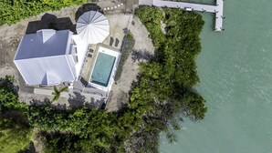 Vista aérea de una propiedad con piscina, terraza cubierta y muelle que se adentra en el agua.