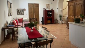 Ein Essbereich mit einem Glastisch, einer roten Tischläufer, Holzstühlen, einem roten Sofa, einem Bücherregal und einem großen, bogenförmigen Durchgang.