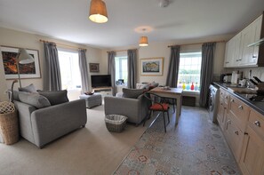 Relax in this stylish living and dining area, featuring a comfortable sofa, dining table, and modern kitchen.