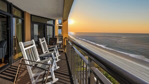 A balcony with a view of the beach and ocean.