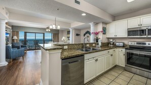 A modern kitchen with white cabinets, a stainless steel dishwasher, and a built-in oven.