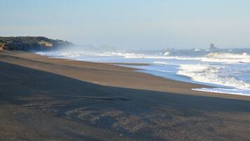 A beach with a clear view of the ocean and distant landforms.