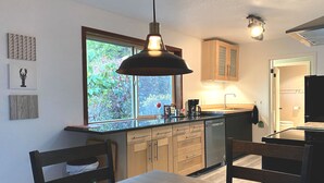 Una cocina moderna con armarios de madera, lavavajillas integrado y un ventanal con vistas a zonas verdes.