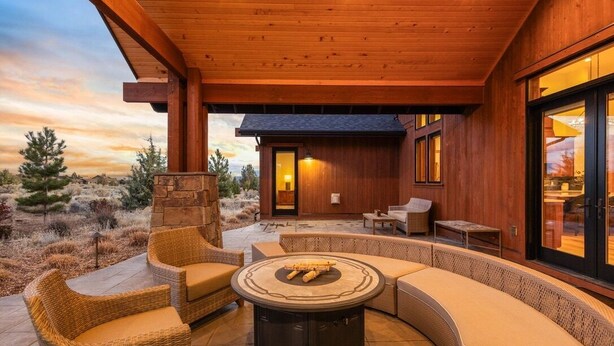 Un patio exterior con mobiliario de mimbre, una mesa redonda y una pared de piedra.