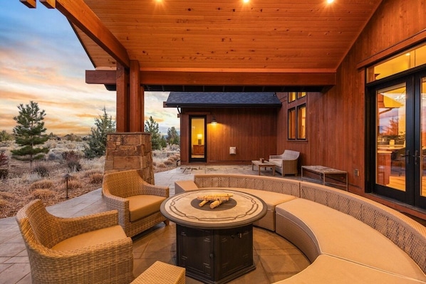 An outdoor patio with wicker furniture, a round table, and a stone wall.