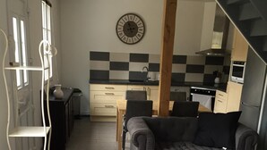 A compact living space with a sofa, a dining table, and a kitchen area. - Gîte 4p Tout confort bord de cher, calme, Animaux ok, Zoo Beauval chenonceau (Bléré)