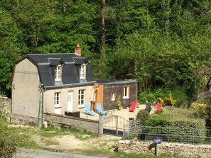 Une maison à deux étages, avec un toit en pente, une cheminée et des fondations en pierre.