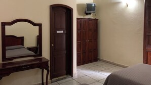 A bedroom with a wooden wardrobe, a bed, a desk, and a television mounted on the wall. - OYO Hotel Real De Cortés (Xalapa)