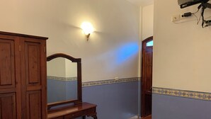 A room with a wooden wardrobe, a desk with a mirror, and a wall-mounted light fixture. - OYO Hotel Real De Cortés (Xalapa)