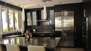 Una cocina moderna con una isla grande, electrodomésticos de acero inoxidable y vistas a palmeras.