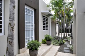 Ein modernes Gebäude mit klarem, minimalistischem Design, große Fenster und ein gepflegter Garten mit Topfpflanzen und einem Weg.
