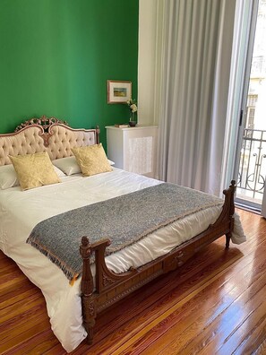 A bedroom with a large bed, green walls, and a wooden floor. - Hotel Chemin (Buenos Aires)