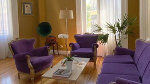 Un salon avec des fauteuils violets, une table basse et une lampe.