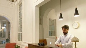 Un comptoir d’accueil avec un ordinateur portable, un lustre et une horloge au mur.