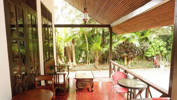 Un espace extérieur abrité, doté de mobilier en bois et offrant une vue sur la végétation tropicale.