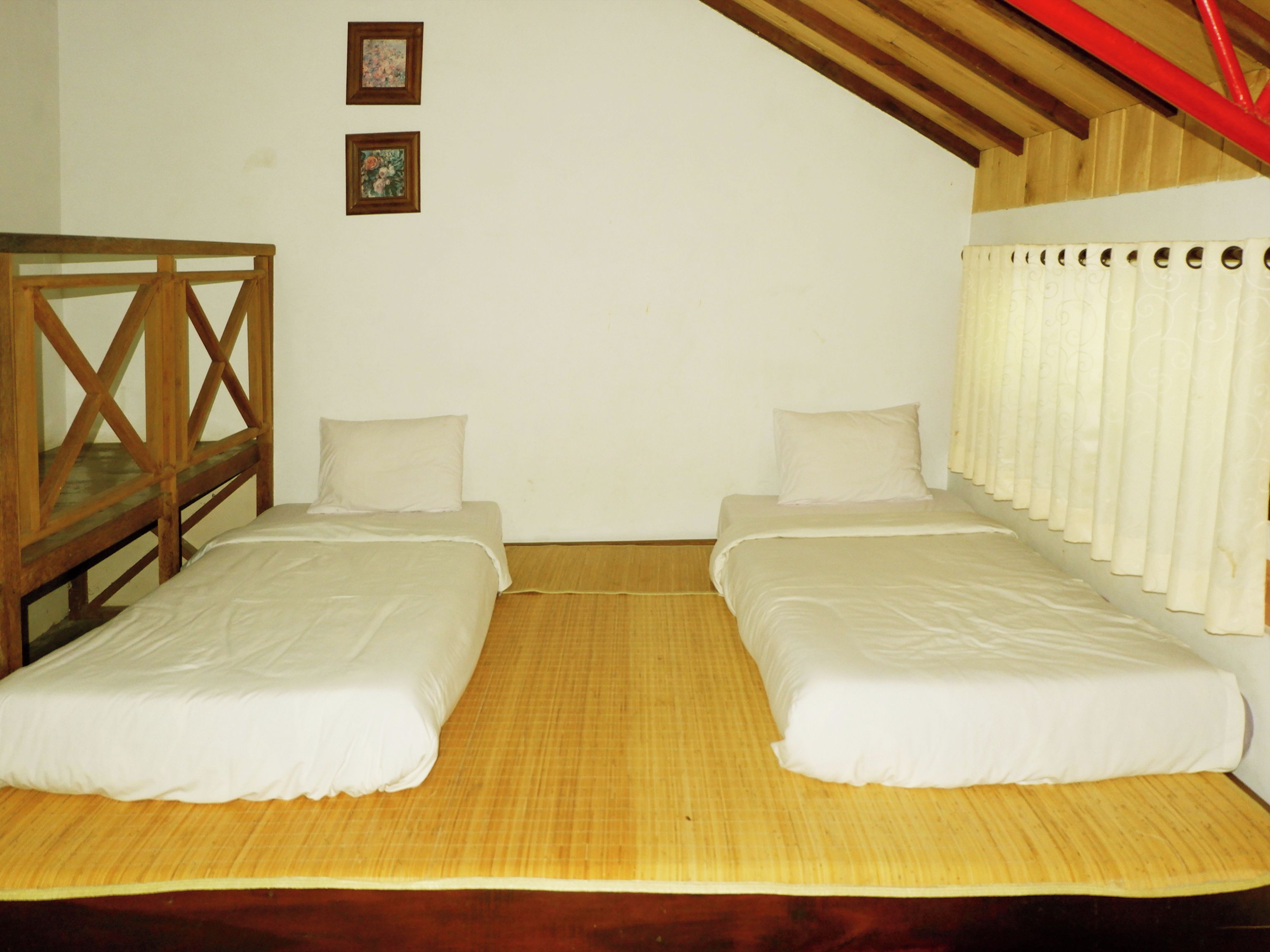 Una habitación con dos camas individuales, un banco de madera y dos cuadros en la pared.