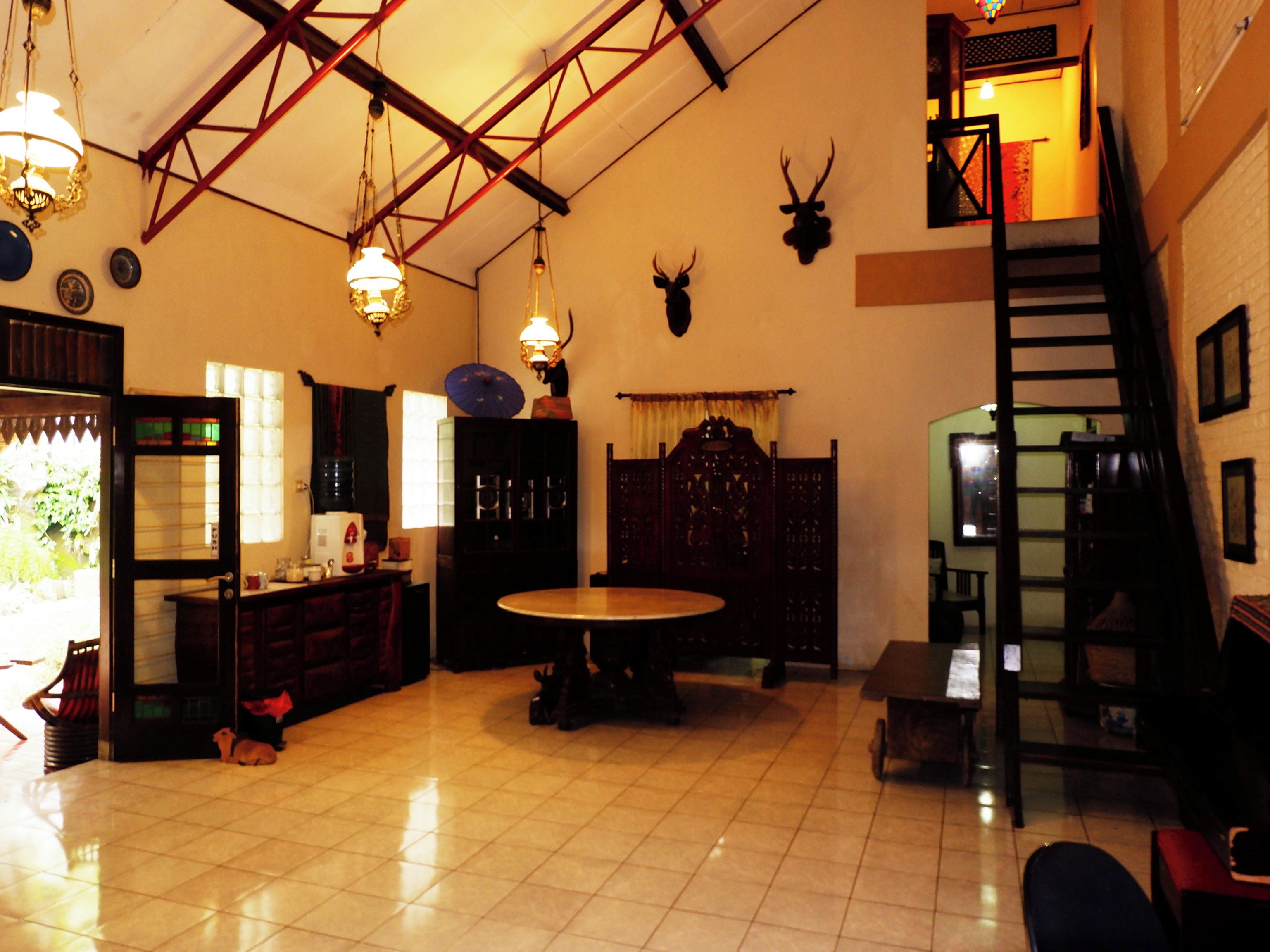 A spacious room with a high ceiling, a staircase, and a dining area with a round table.