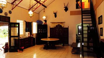 A spacious room with a high ceiling, a staircase, and a dining area with a round table.
