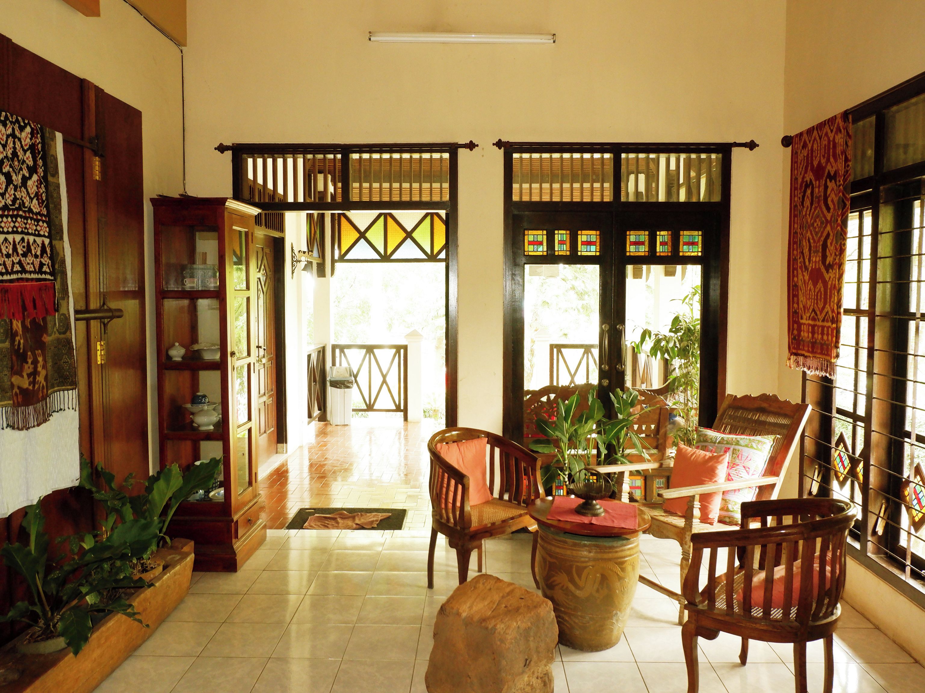 A traditional interior with a wooden floor, a central seating area with chairs and a table, and a bookshelf.