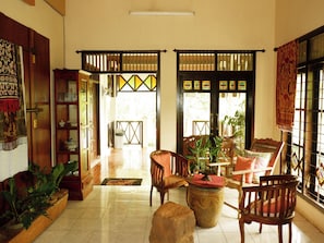 A traditional interior with a wooden floor, a central seating area with chairs and a table, and a bookshelf. - OYO 604 Cemara S Homestay (Batu)