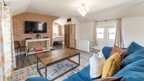 Un salon avec un mur en briques, une télévision, un canapé et une table basse.