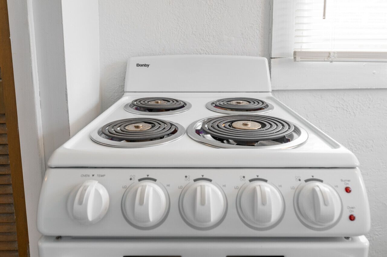A white Danby stove with four burners and five control knobs.
