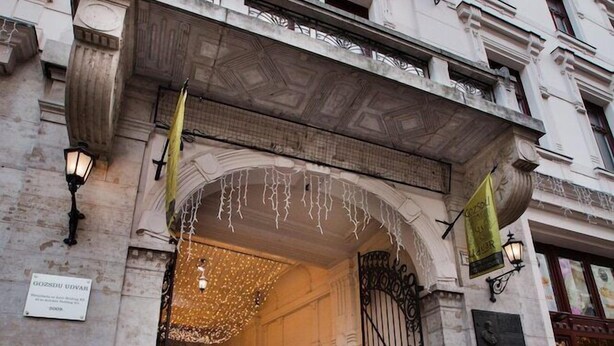 A historic building with an ornate entrance, a sign indicating a restaurant, and a cobblestone street. - Hotel Gozsdu Court Ex Gozsdu Court Apartment (Budapest)