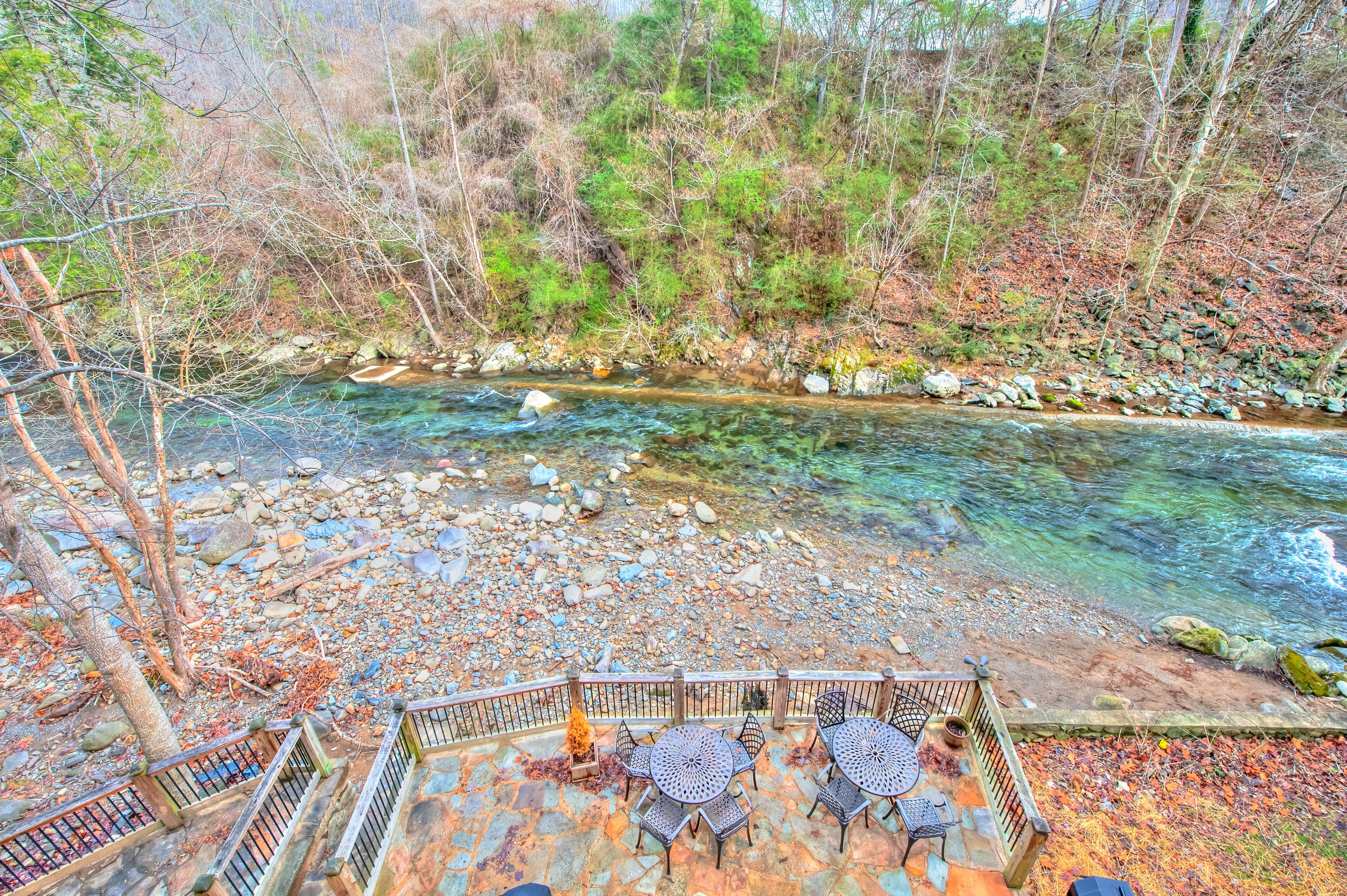 Un patio sul fiume con posti a sedere all'aperto e vista su un corso d'acqua limpido.