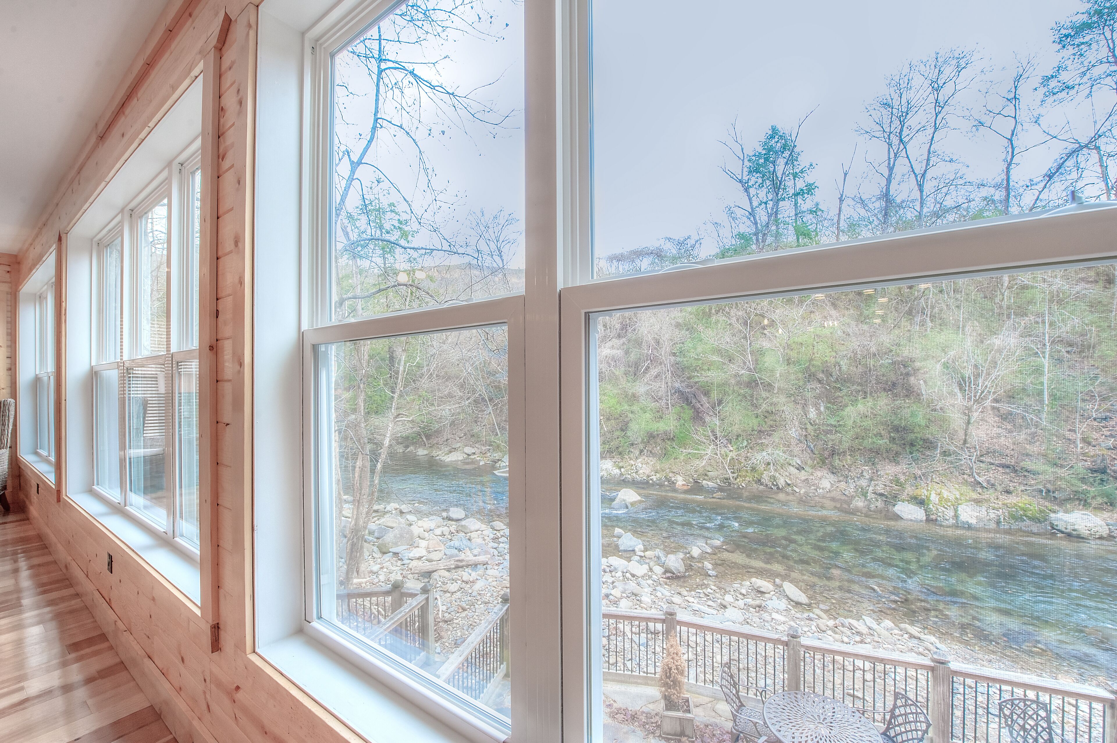 A room with large windows overlooking a river and trees.